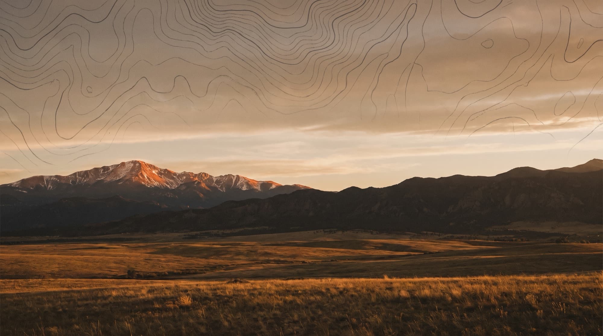 Alpenglow on the snow-dusted summit of Pikes Peak over the open grassland of El Paso County, Colorado at dusk