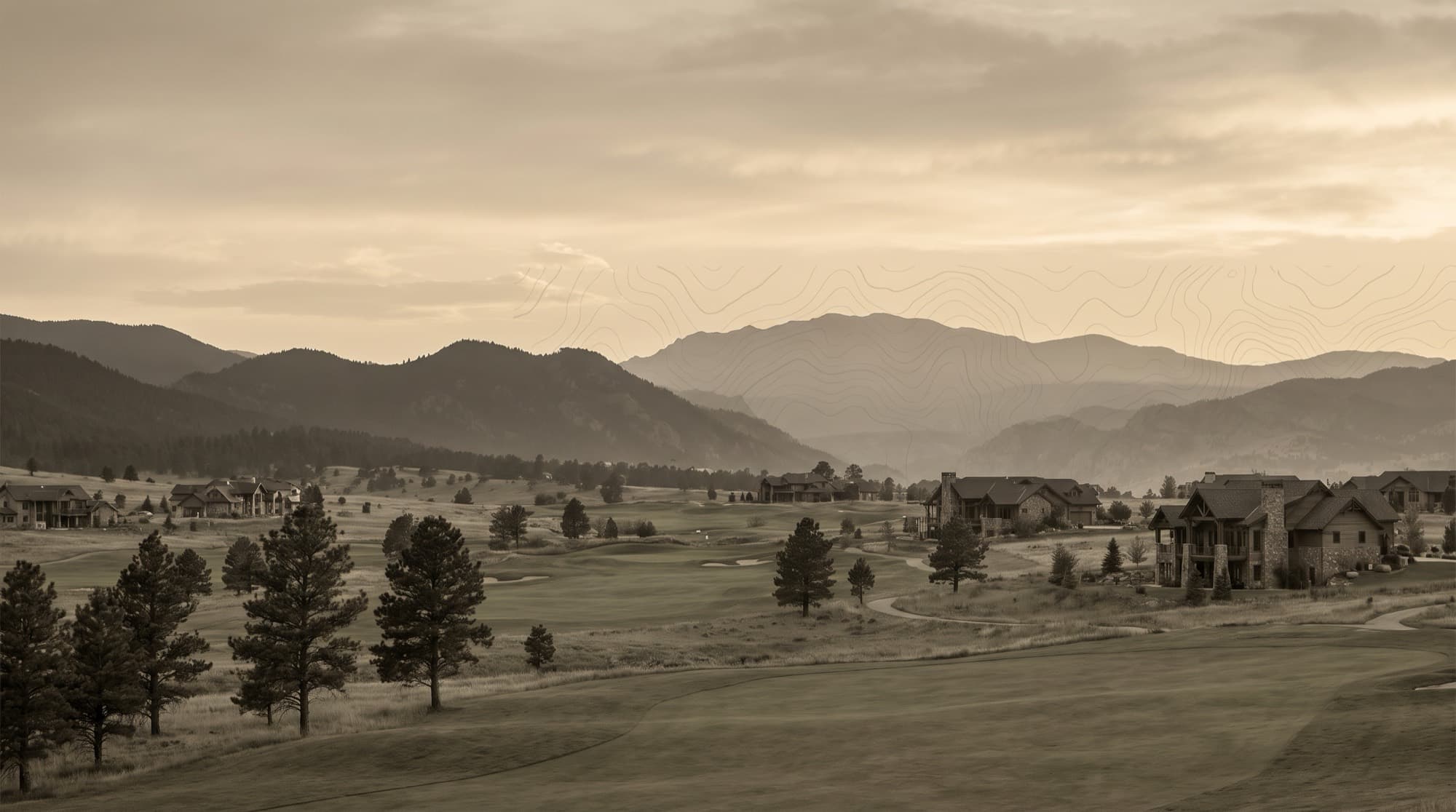 Rolling golf fairways and ponderosa pines among refined homes in Gleneagle, Colorado, below the forested Rampart Range and Air Force Academy foothills at dusk